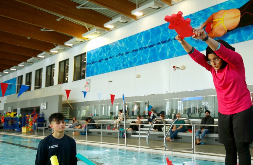 Swim-instructor-looks-on-a-young-person-practices-a-dive