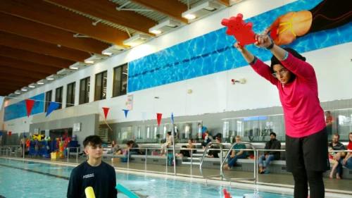 Swim-instructor-looks-on-a-young-person-practices-a-dive