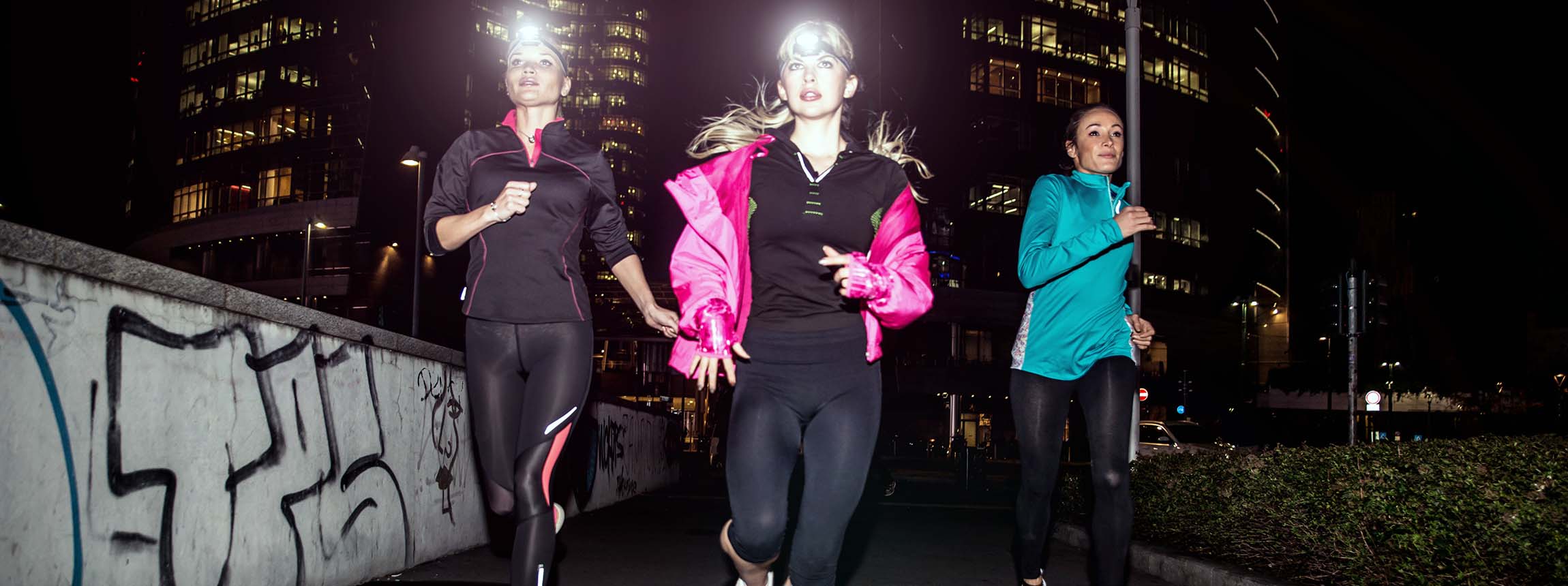 Three women running in the night in the city centre