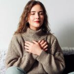 Woman practicing pranayama in lotus position on bed, breathing exercises to reduce stress and anxiety