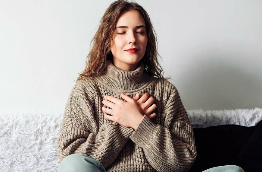 Woman practicing pranayama in lotus position on bed, breathing exercises to reduce stress and anxiety