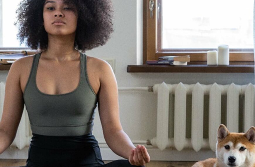 woman practices yoga with dog watching on