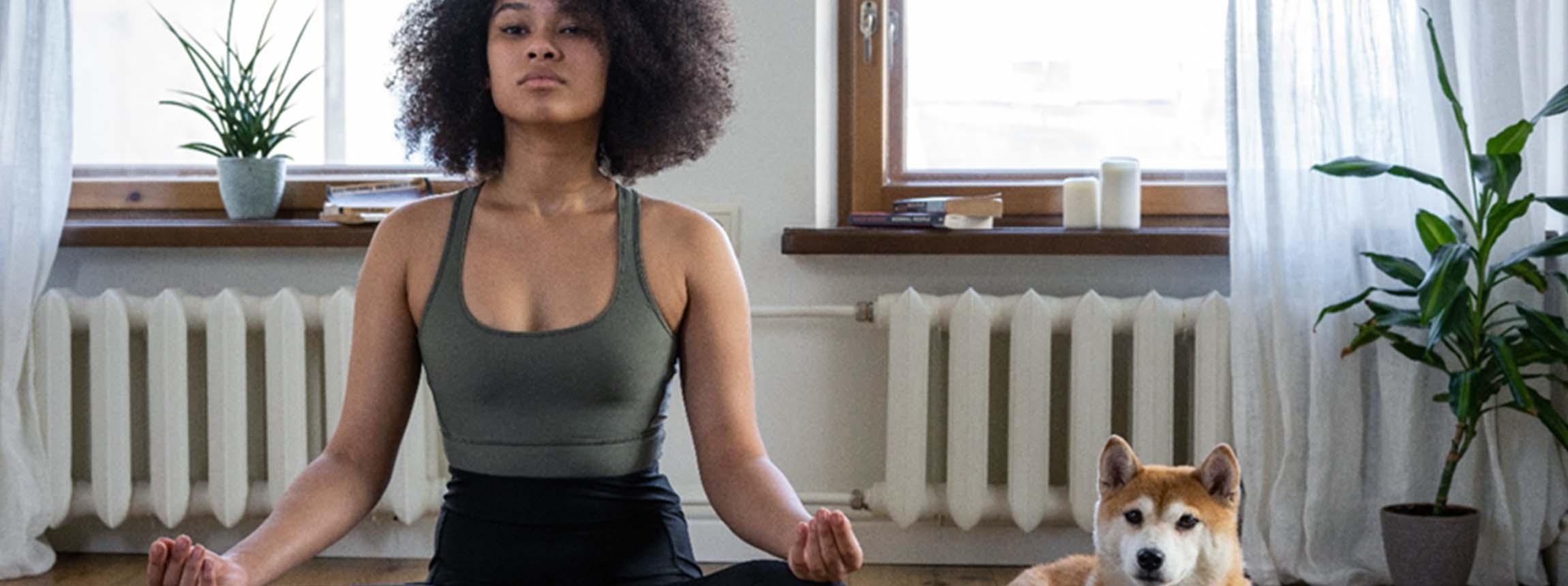 woman practices yoga with dog watching on