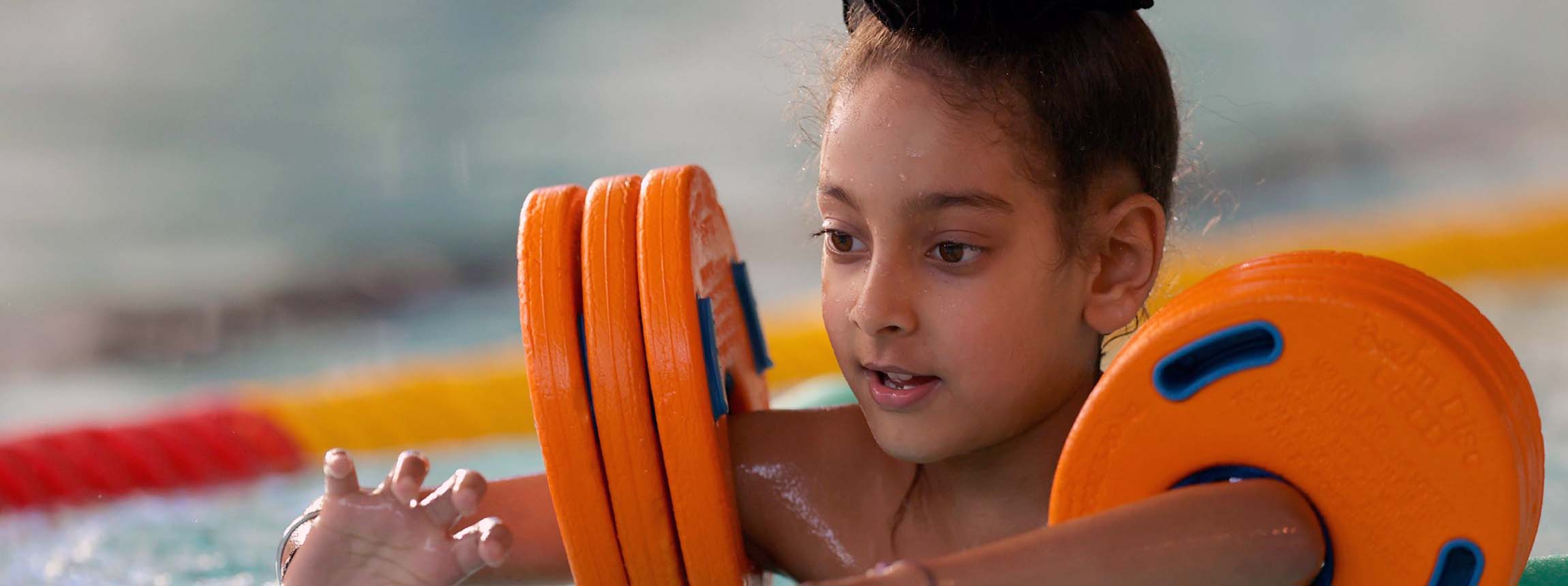 young girl swims with arm bands on