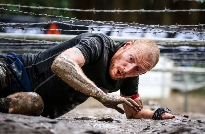 Tough Mudder Participant climbs under barbed-wire