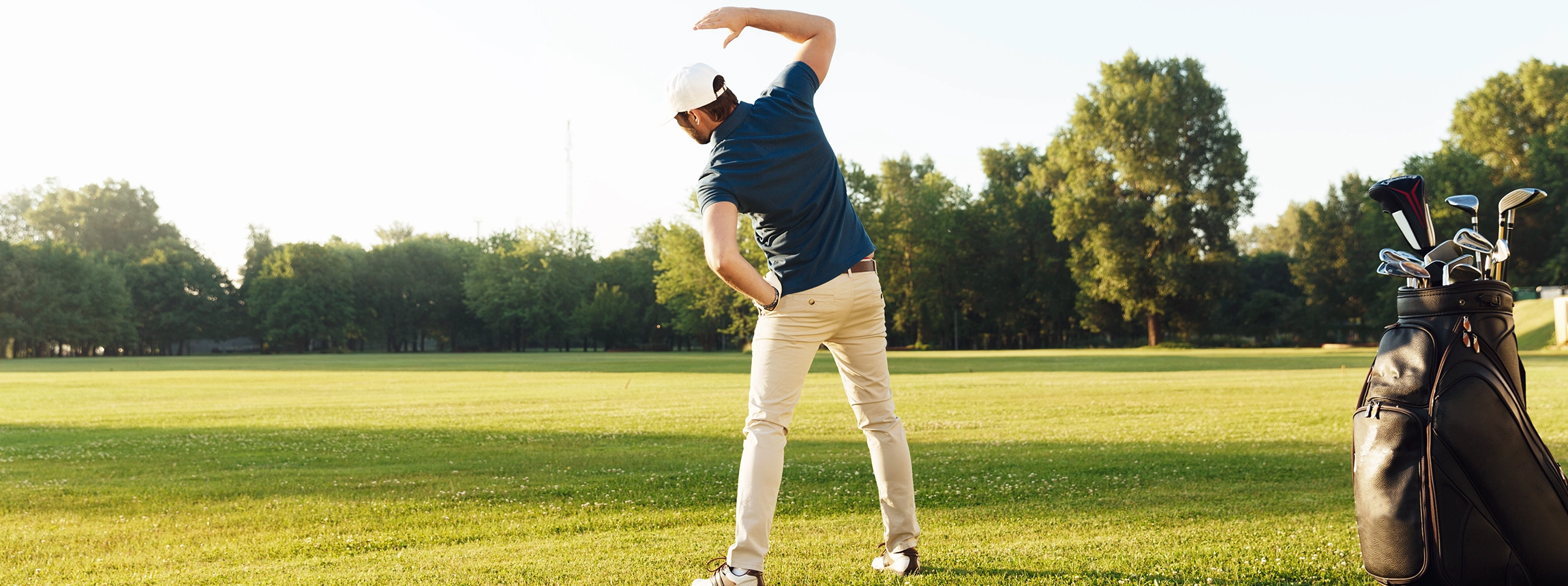 Young male golfer stretching muscles before starting the game