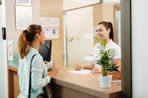 Happy woman talking to a receptionist while arriving at the spa