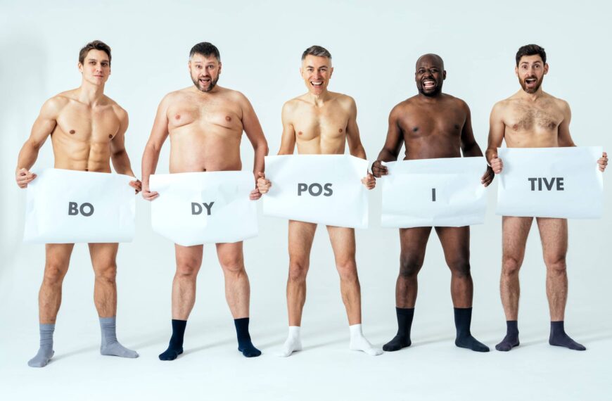 men posing for a male edition body positive beauty set showing messages on banners.