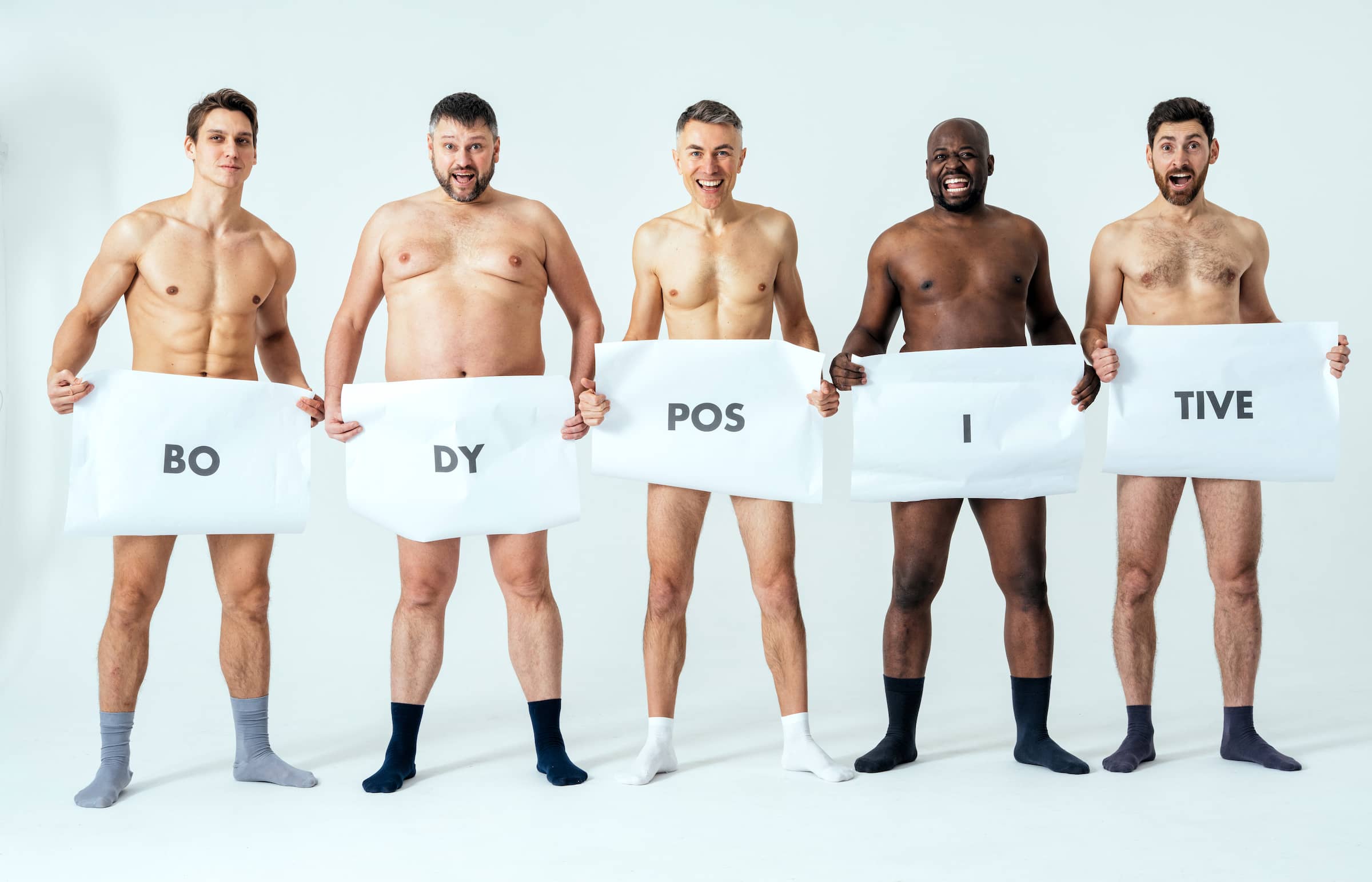 men posing for a male edition body positive beauty set showing messages on banners.