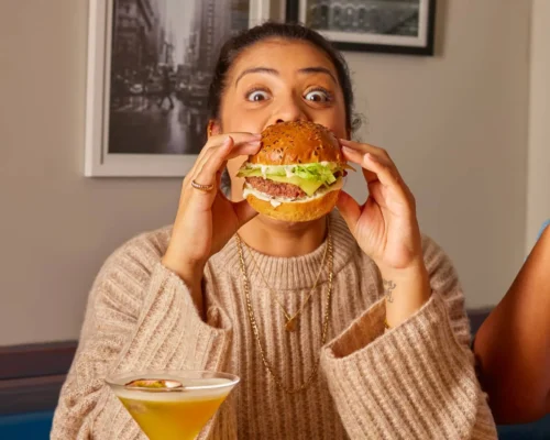 person bites into Frankie n Benny's burger