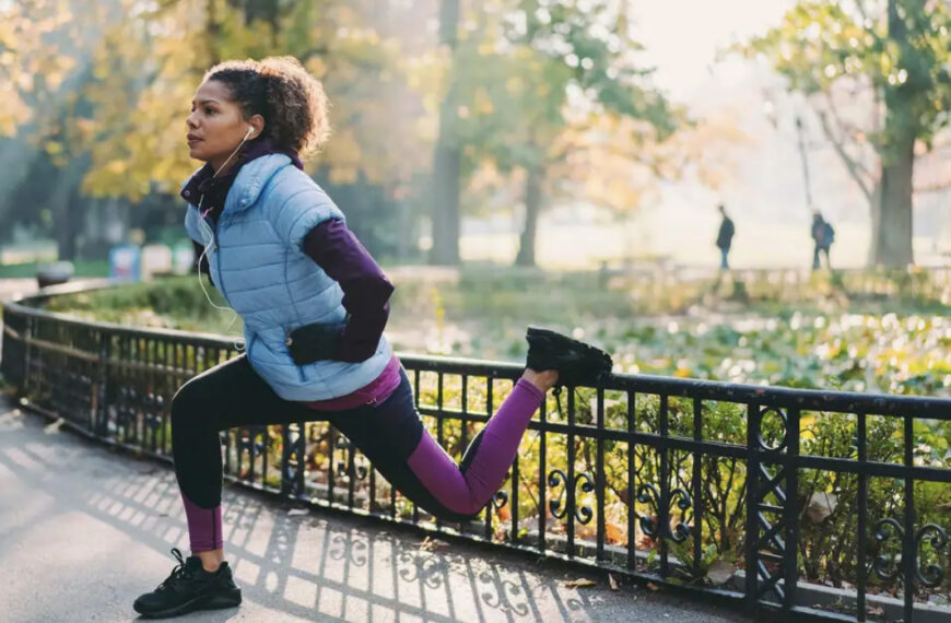 woman stretches in autumnal looking park