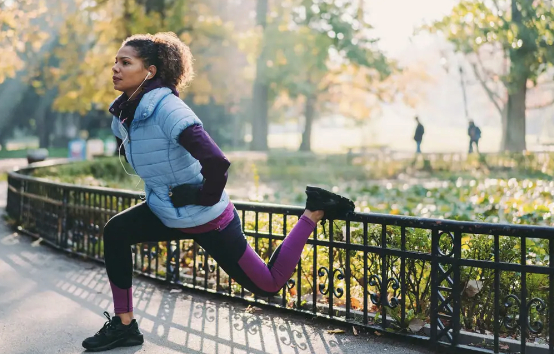 woman stretches in autumnal looking park