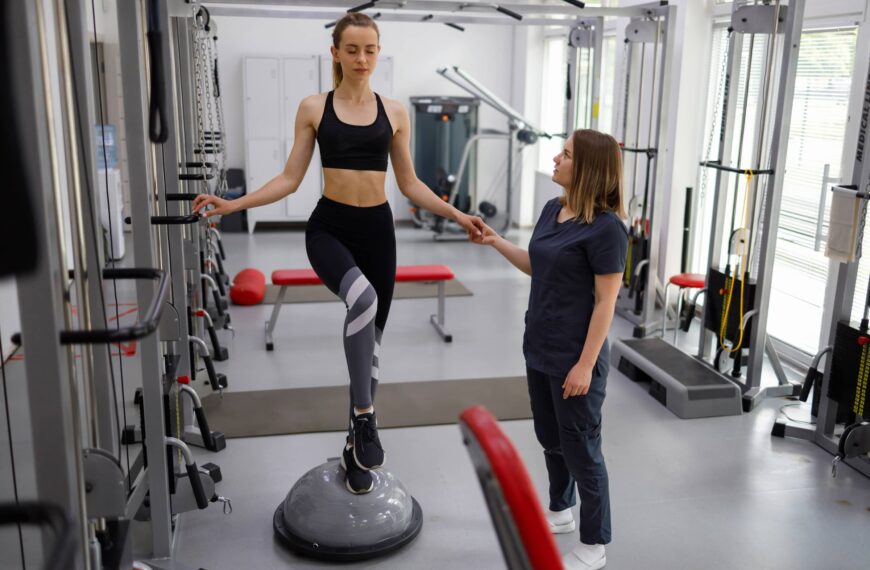 Physiotherapist helping female patient with rehabilitation. Balance exercise with bosu ball.