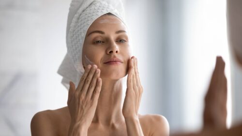 woman applying moisturising creme on face after shower