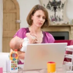 Mother and baby in home office with laptop