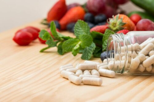 Supplement pills on table with fruit in background