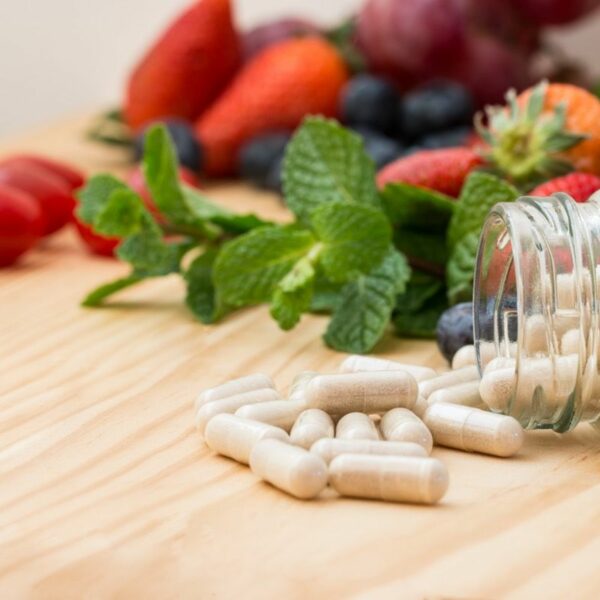 Supplement pills on table with fruit in background