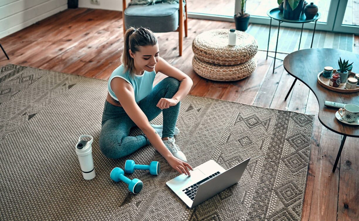 Woman in gym wear looks at laptop