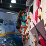 Young person climbs indoor rock wall