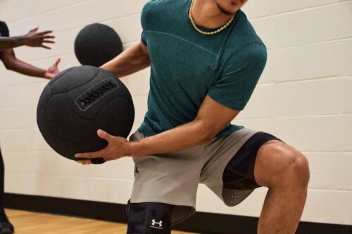 Fitness Person wearing Under Armour activewear throws medicine ball