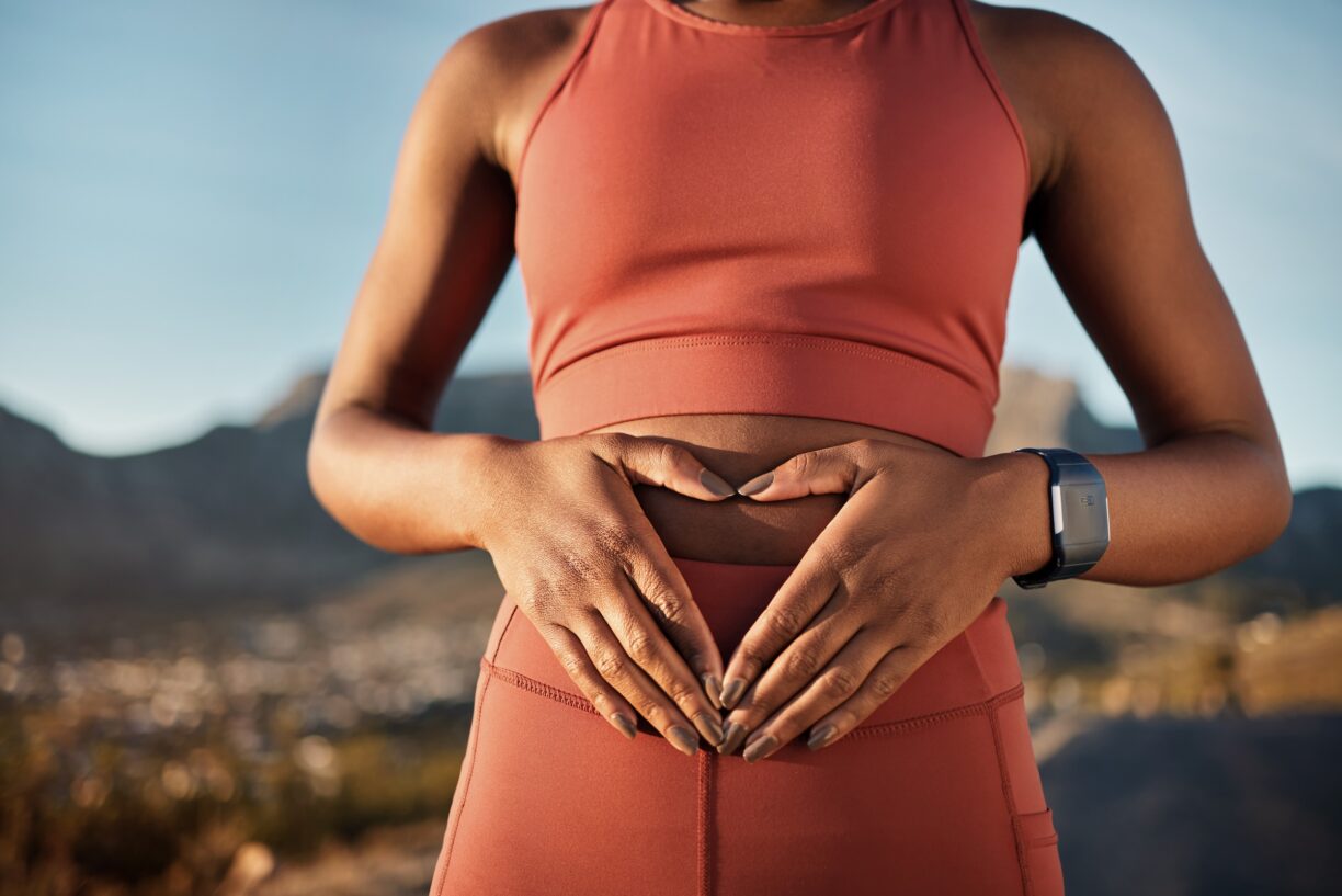 Person-holds-hands-on-stomach-to-make-heart-sign