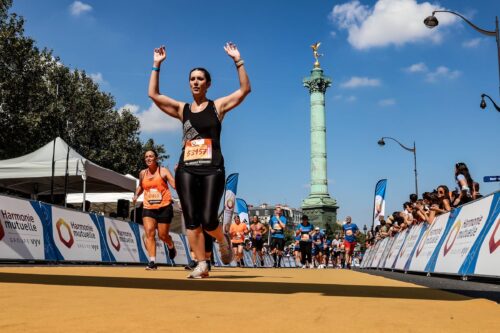 Runner celebrates with hands raised across the running line