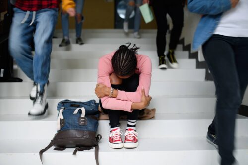 Depressed young student sitting on floor back at college or university