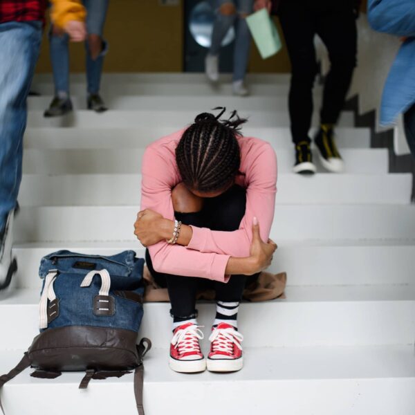 Depressed young student sitting on floor back at college or university