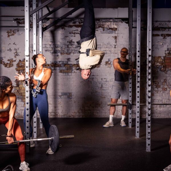 Escapologist Hanging Upside Down With Class Members Around