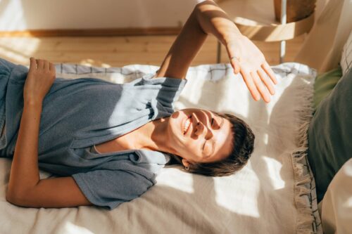 Sunbeams in the room, a woman lies on a bed in the sunbeams