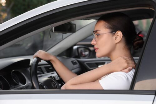 Young woman suffering from neck pain in her car