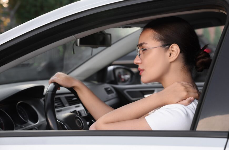 Young woman suffering from neck pain in her car