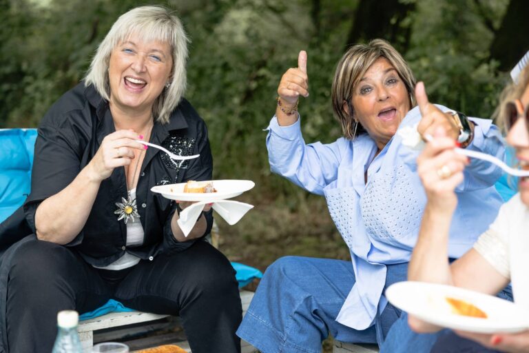 Joyful mature women enjoying food and friendship at a picnic.