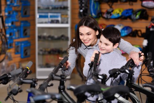 Young mother with son looking at bicycles in bike shop