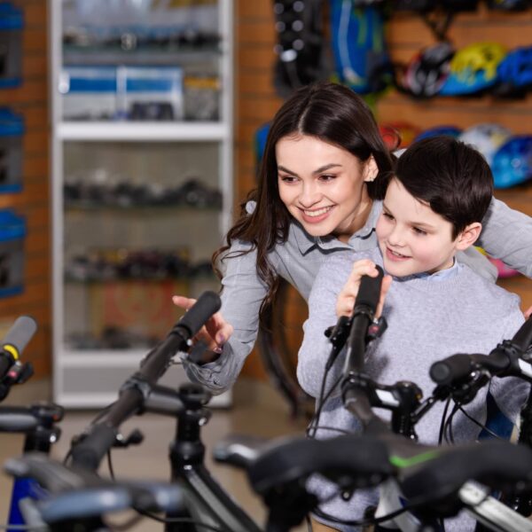 Young mother with son looking at bicycles in bike shop