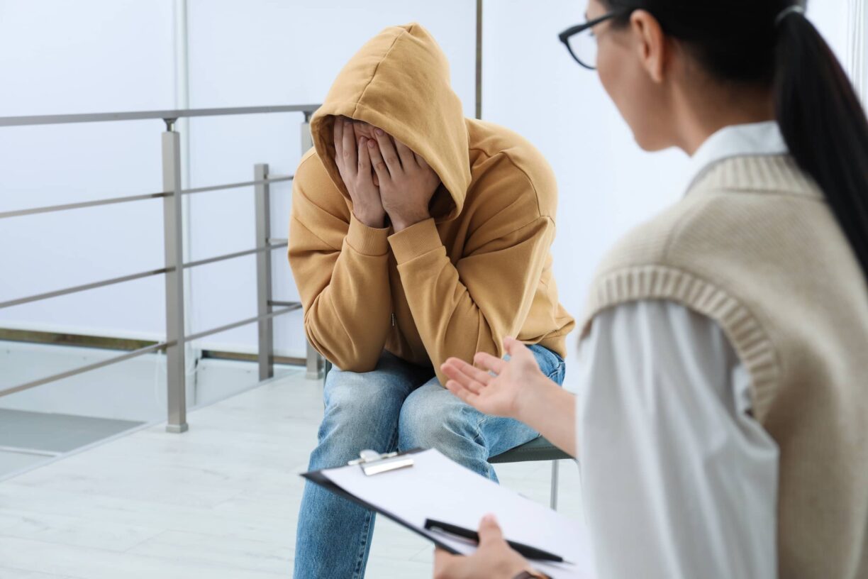 Person holds hands over face being counselled