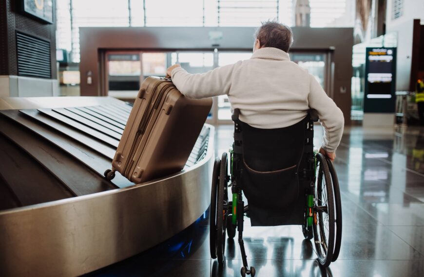 Rear view of man on wheelchair at airport with his luggage