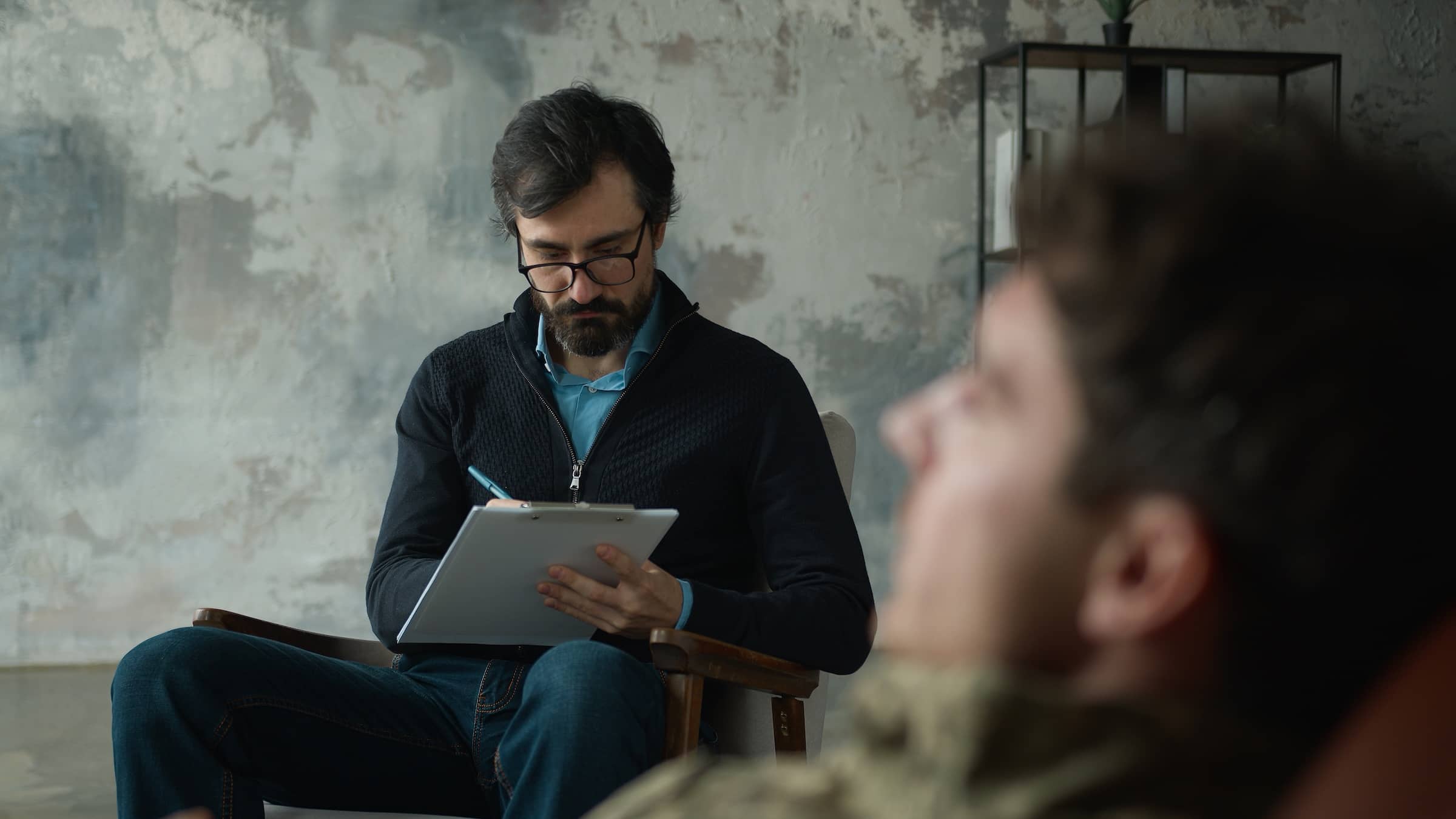 psychologist counselor writing notes listening patient client