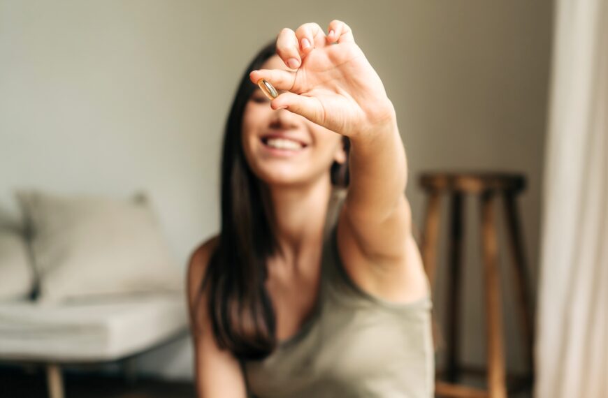 Happy healthy woman recommending omega 3 fish oil and holding out a pill in her hand