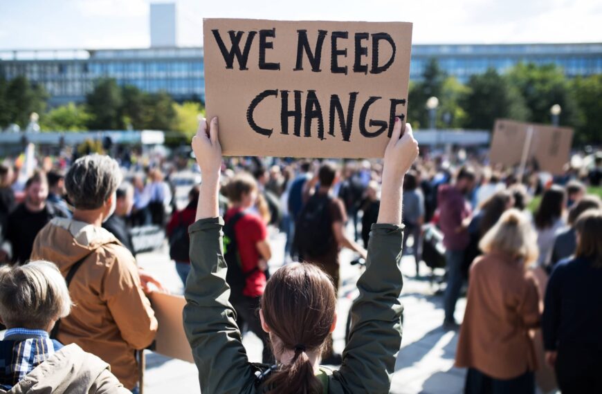 Person holds placard saying we need change