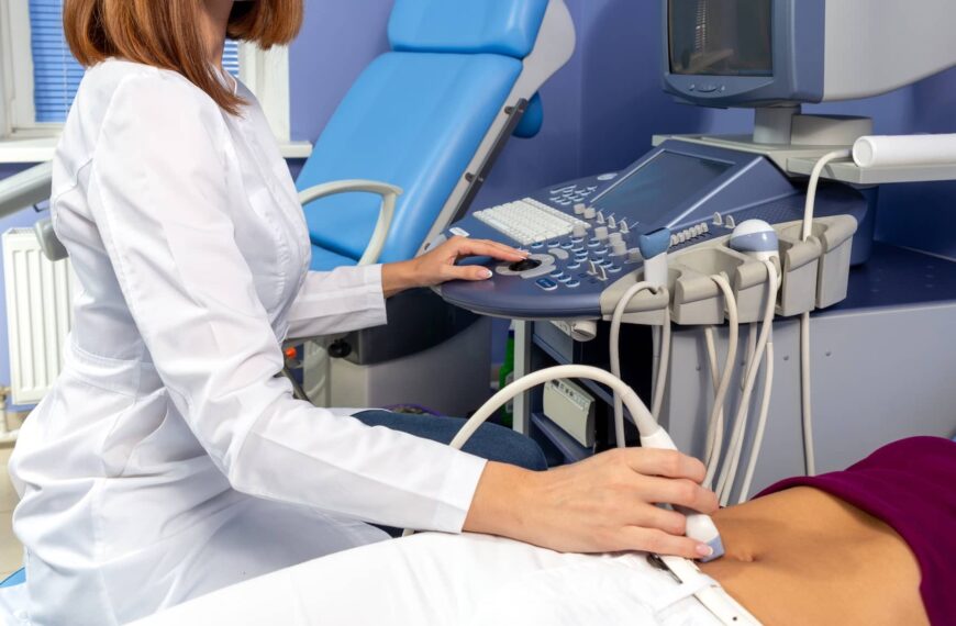 The doctor performs an ultrasound diagnosis of the abdominal cavity of a pregnant girl at an early stage of pregnancy.