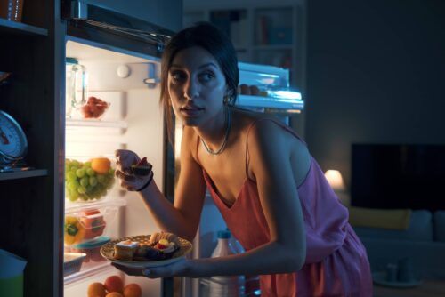 Hungry woman eating sweets at night