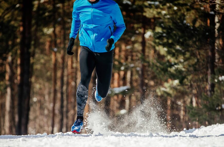 Runner running winter trail, splashes of snow underfoot