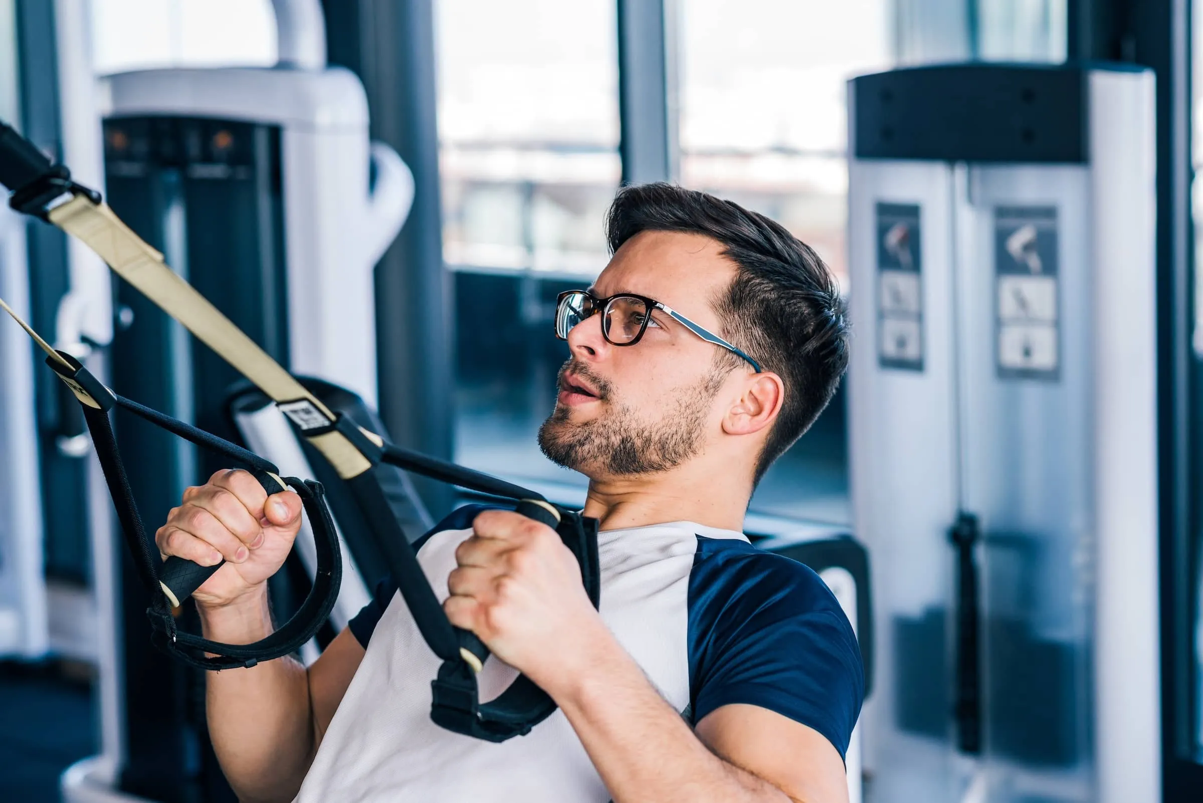 Close-up of sportsman in eyeglasses working out on TRX