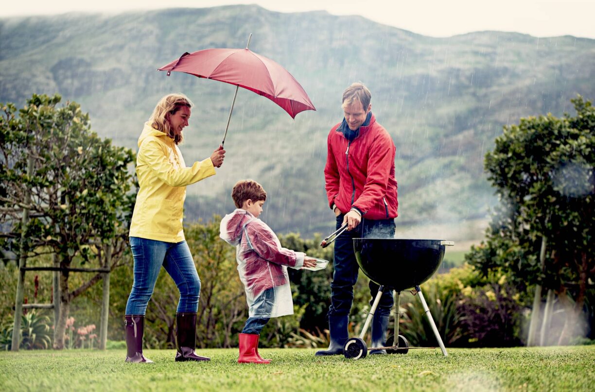 Family having a barbecue outside in rainy weather