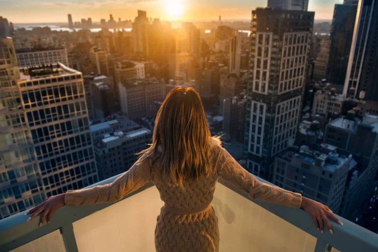 woman enjoys the sunset standing on the balcony at luxury apartments in New York City