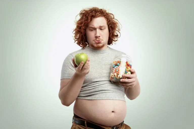 Overweight man looks at apple and sweets