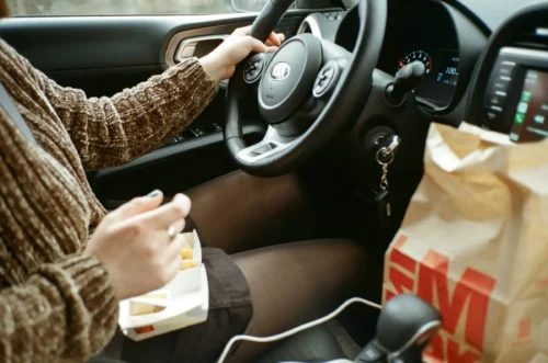 Person drives whilst eating fast food