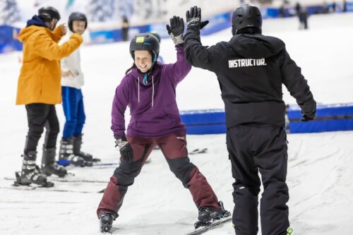 Person high fives ski instructor on slope