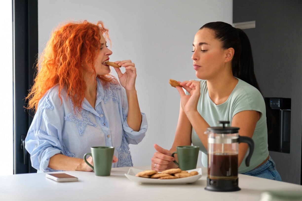 Mother and daughter, eating cookies and coffee